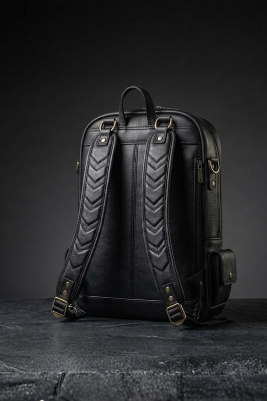 Batman inspired genuine leather backpack back view showing jet black body with chevron quilted padded shoulder straps, antique bronze buckles and side zip pocket detail