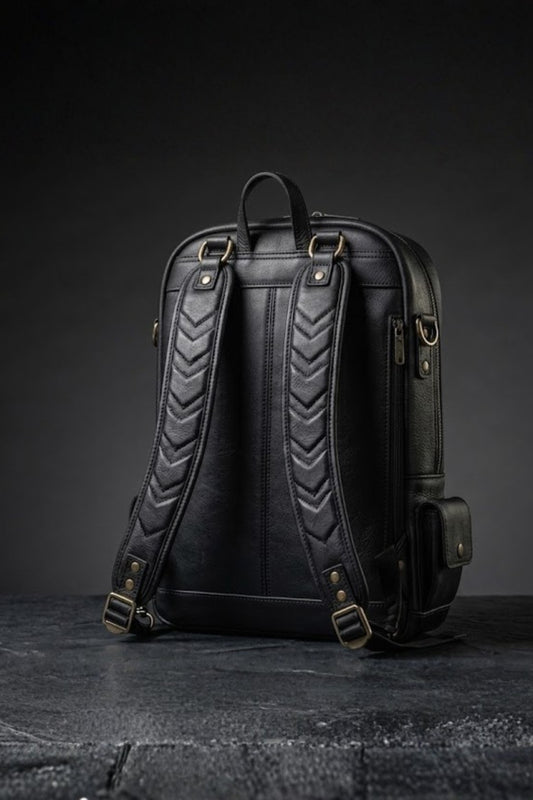 Batman inspired genuine leather backpack back view showing jet black body with chevron quilted padded shoulder straps, antique bronze buckles and side zip pocket detail