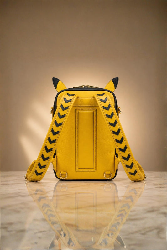 Back view of Pikachu inspired genuine leather backpack in yellow with black chevron arrow patterned shoulder straps, sculpted ears and gold zipper hardware