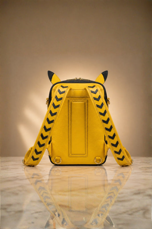 Back view of Pikachu inspired genuine leather backpack in yellow with black chevron arrow patterned shoulder straps, sculpted ears and gold zipper hardware