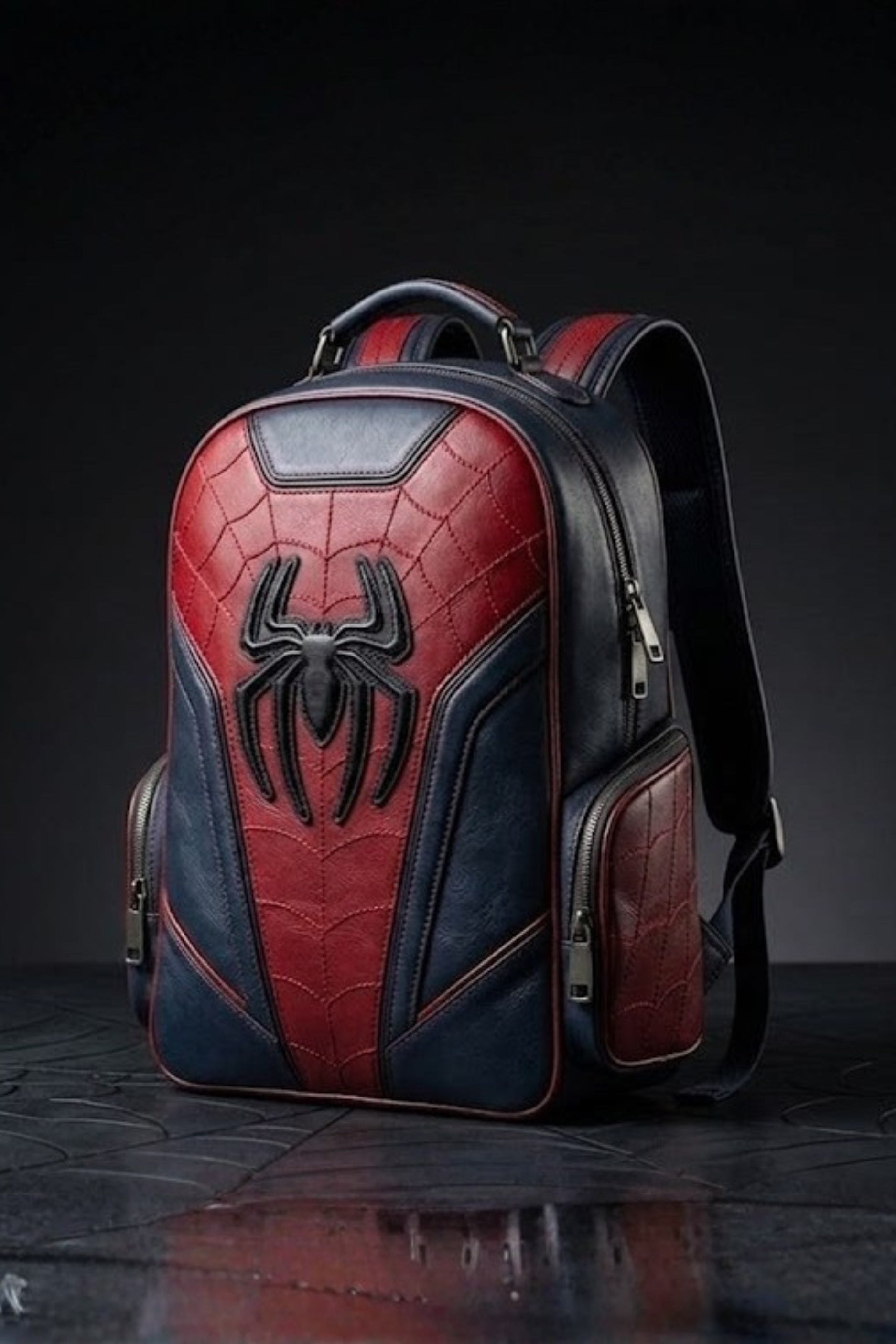 Spider-Man inspired red and navy blue leather backpack with embossed 3D spider logo and web stitch quilted pattern, front view